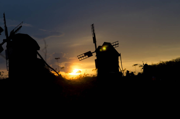 Silhouettes of old windmills on the background of bright blue sky sunset - Foto, immagini