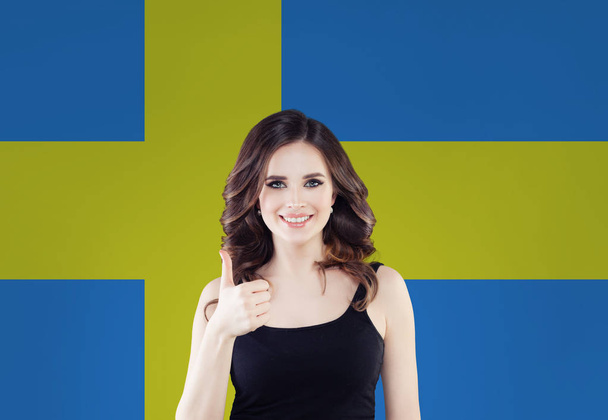Suécia. Menina estudante feliz com polegar contra a bandeira da Suécia
 - Foto, Imagem