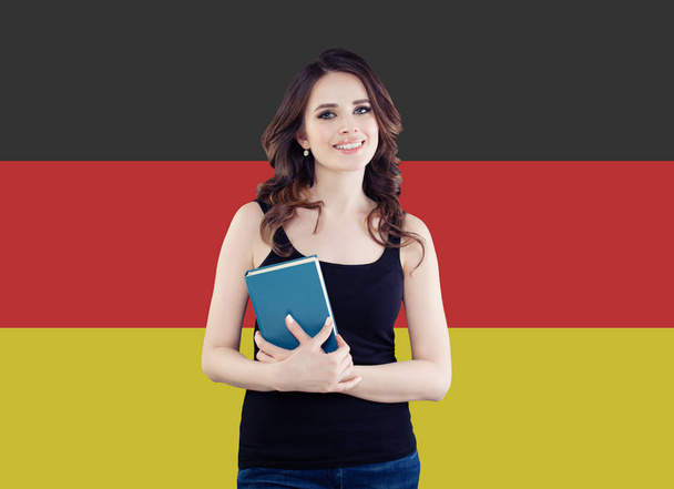 Portret van gelukkige jonge vrouw die lacht tegen de achtergrond van de vlag Duitsland.  - Foto, afbeelding