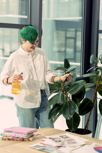 Joyful green haired woman standing near the green plant - Photo, Image