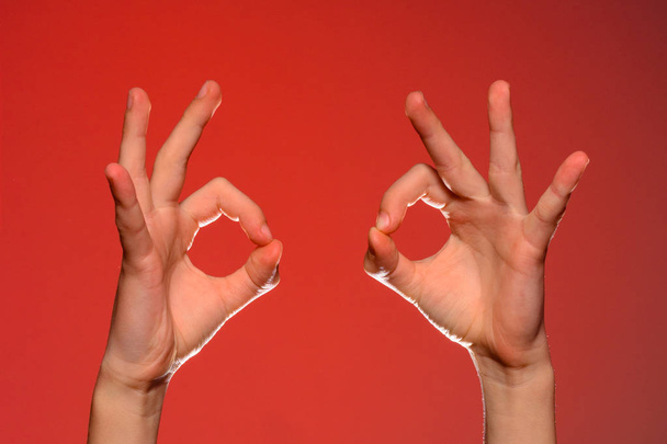 Kaksi ihmisen kädet osoittavat merkki ok, eristetty punaisella taustalla
 - Valokuva, kuva