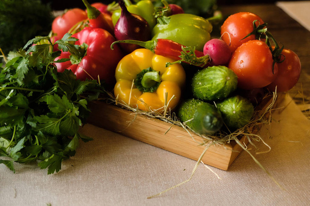 新鮮な野菜やハーブの木製の背景に木製の箱のグループ。キュウリ、パプリカ、ピーマン、キュウリ、トマト、ハーブ。収穫と健康的な有機食品のコンセプト - 写真・画像