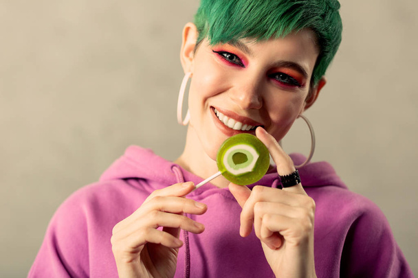 Nice pretty woman touching a green lollipop - Fotó, kép