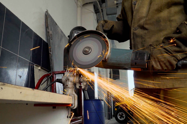 Työntekijän lähikuva hiomakoneen avulla leikkaa metallia työpajassa - Valokuva, kuva