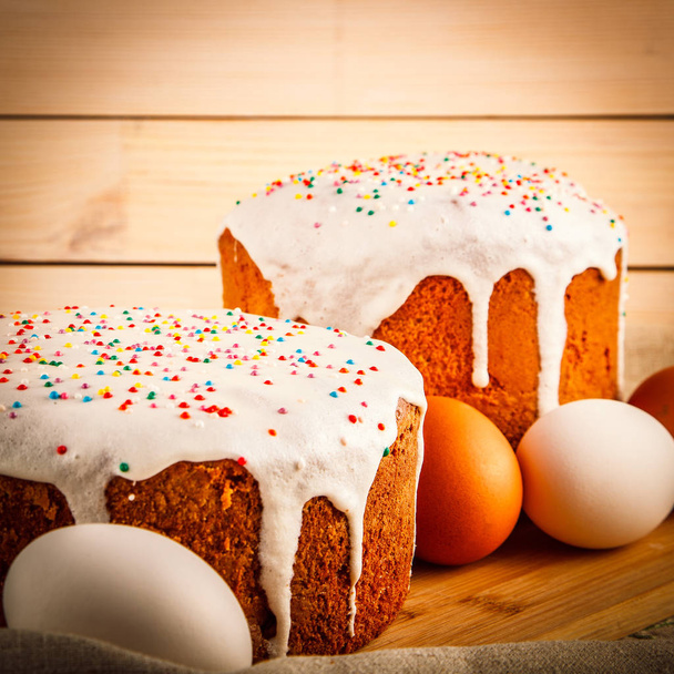 Easter symbols, easter eggs and cakes on wooden background - Photo, image