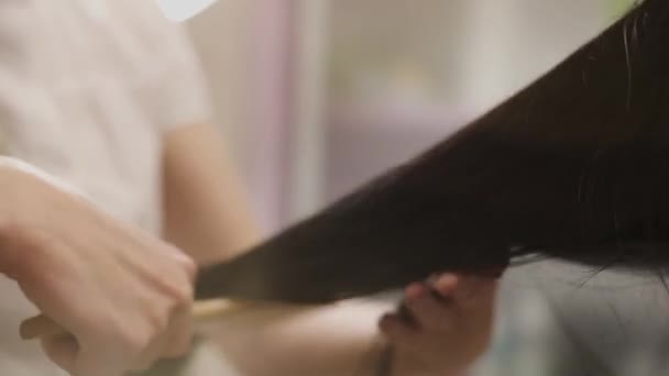 salon fryzjerski łączy piękne czarne włosy - Materiał filmowy, wideo