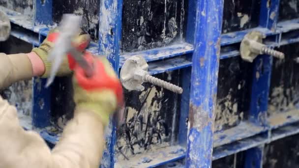Un empleado en la construcción con la ayuda de un martillo gira la fijación del soporte de hormigón
. - Metraje, vídeo