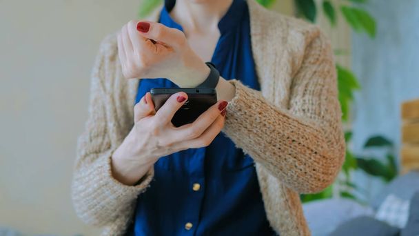 Nainen synkronoi puettavat kunto tracker tiedot älypuhelin app
 - Valokuva, kuva