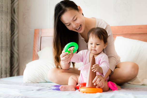 Mãe feliz ensina habilidades de coordenação filha de 2 anos usando brinquedos de aro de plástico
 - Foto, Imagem