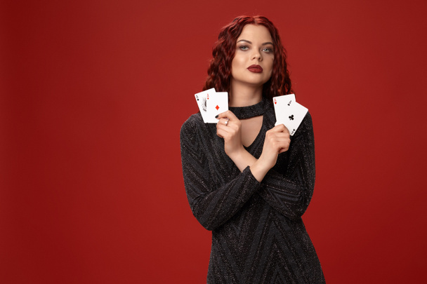 Красивая рыжая женщина держит в руках игральные карты. Казино
 - Фото, изображение