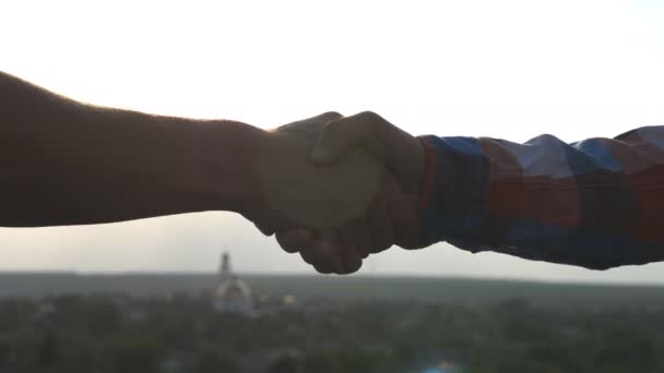 Close up of two friends meeting on rooftop and doing secret friendly handshake outdoor. Young men greeting each other and shaking hands on cityscape background. Concept of friendship. Slow motion - Footage, Video