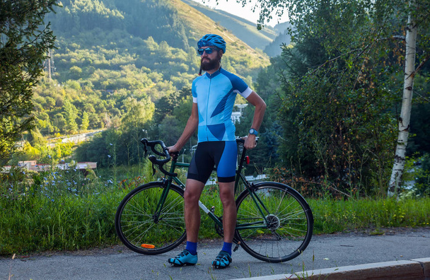 Mann mit Fahrrad in den Bergen. Straße in den bewaldeten Bergen. - Foto, Bild