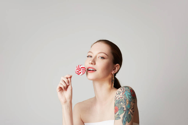 Fashion portrait pretty sweet young woman having fun with lollipop over empty white background - Zdjęcie, obraz