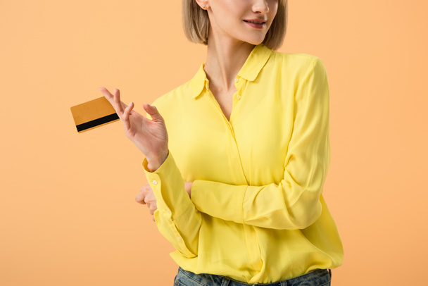 Cropped view of stylish young woman holding credit card isolated on orange - Fotoğraf, Görsel