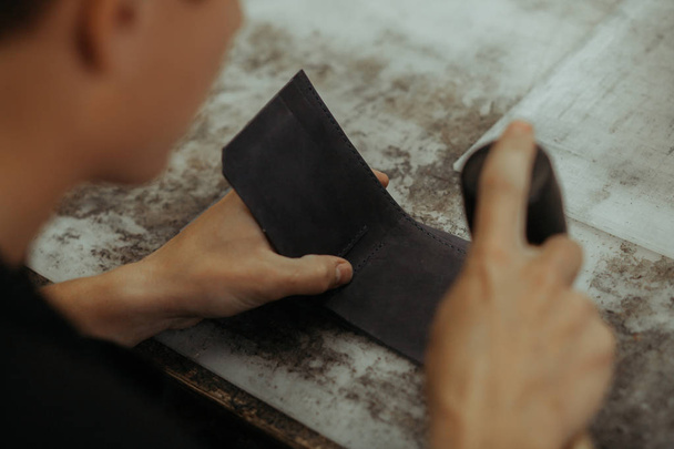 Close up of leather craftsman working with natural leather. Handmade master at work in local workshop. Handmade concept. - Foto, Bild