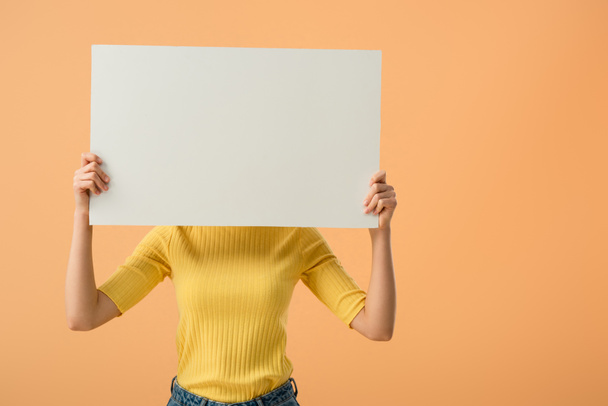 Young woman in yellow jumper holding blank placard isolated on orange - Foto, afbeelding