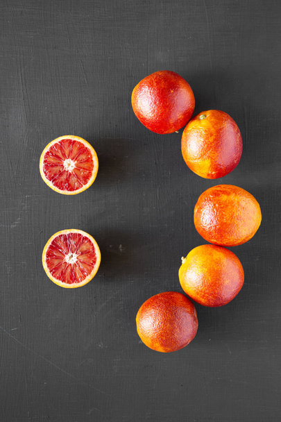 Oranges sanguines entières et coupées en deux sur fond noir, vue de dessus. F
 - Photo, image
