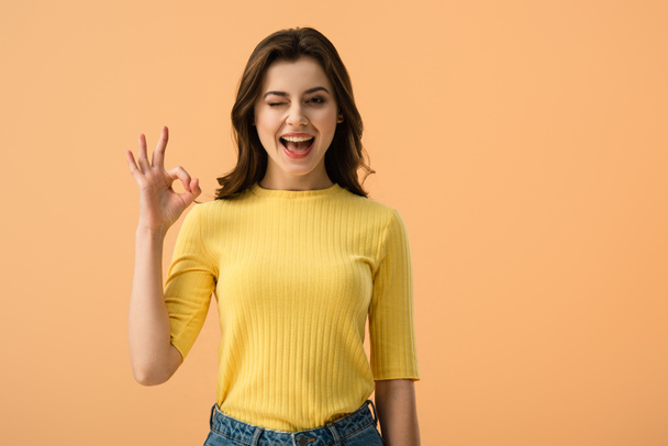 cheerful brunette girl showing ok sign isolated on orange  - Fotografie, Obrázek