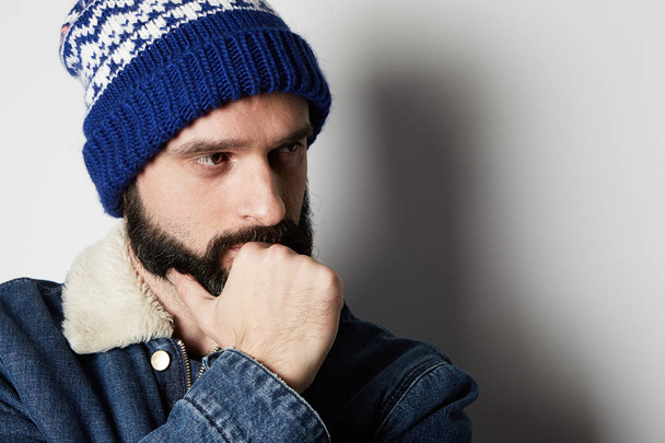 Pensive Bearded man Wearing blue jeans jacket and beanie on white background. Studio shot. - 写真・画像