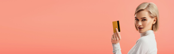 panoramic shot of attractive blonde woman holding credit card isolated on pink  - Foto, Imagem