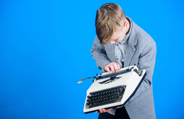 Przy użyciu maszyny do pisania. Małe dziecko zatem na stara maszyna do pisania. Smart uczniak z rocznika do pisania. Ładny chłopak z maszyny do pisania. Mały chłopiec gospodarstwa retro do pisania na niebieskim tle, miejsce - Zdjęcie, obraz