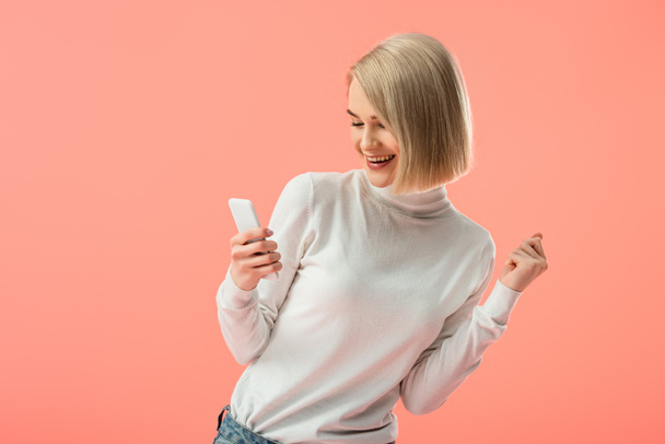 cheerful blonde girl using smartphone isolated on pink  - Фото, изображение