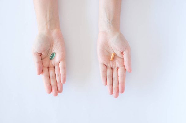 vitamins pills medications biological supplements green and orange oval tablets lie in the palms of the hands on a white background - Foto, Imagem