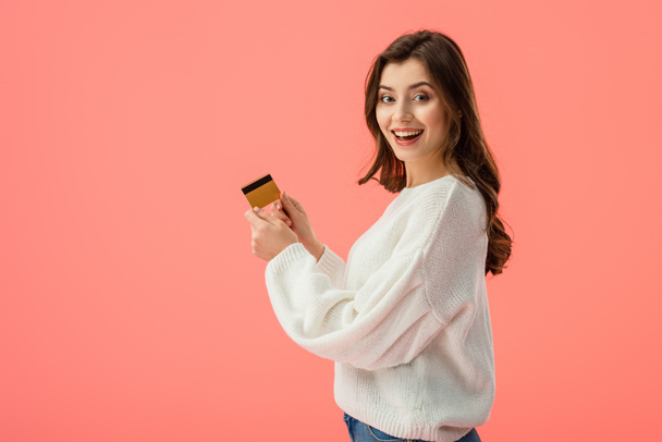 happy brunette girl holding credit card isolated on pink - 写真・画像