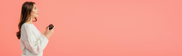 панорамный снимок удивленной девушки, держащей джойстик, стоящей изолированной на розовом
  - Фото, изображение