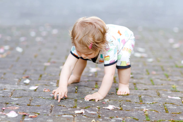 Linda niña adorable haciendo los primeros pasos al aire libre. Saludable niño feliz aprendiendo a caminar. Chica encantadora disfrutando de jardín de primavera. - Foto, imagen