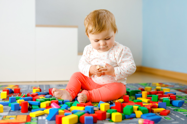 Roztomilá holčička si hraje se vzdělávacími hračkami. Šťastné zdravé dítě baví s barevnými různé dřevěné bloky doma v domácím pokoji. Baby učení barvy a formy - Fotografie, Obrázek