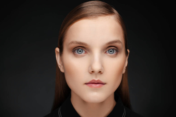 Close-up portrait of a beautiful model with clean makeup and collected hair, photographed in a photo studio - 写真・画像