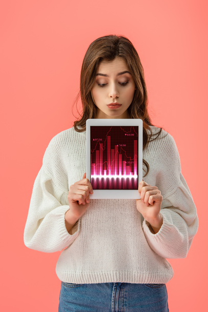 hübsche junge Frau hält ein digitales Tablet mit Diagrammen auf dem Bildschirm, isoliert auf rosa  - Foto, Bild