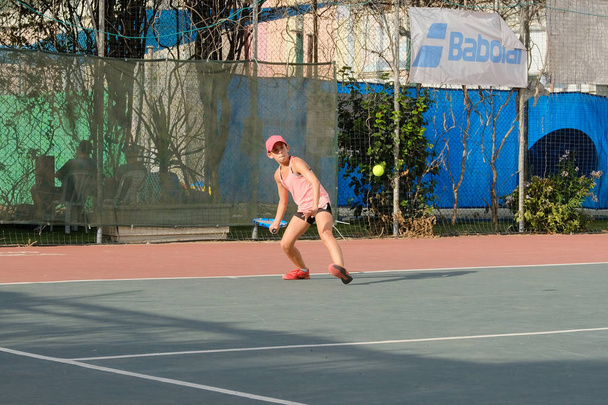 Israël - Netanya, 27 juli 2018: meisje tiener speelt tennis tennis swarty sporting met een grote racket batting de bal maakt een feed wordt uitgevoerd op de rechtbank op wedstrijden in Israël - Foto, afbeelding