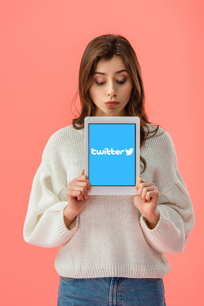 surprised young woman holding digital tablet with twitter app on screen isolated on pink  - Foto, Bild
