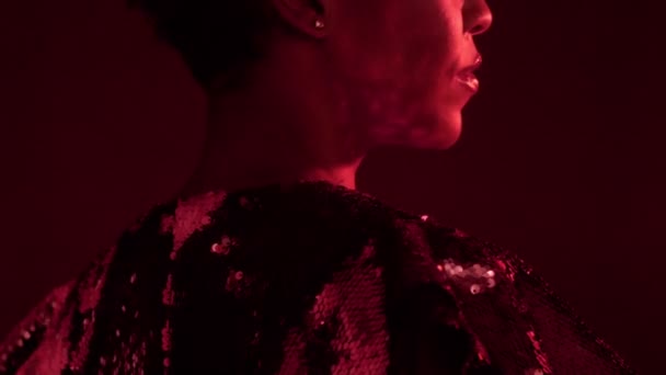 woman in sparkly dress in red light in nightclub - Video, Çekim
