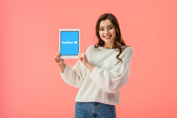 happy young woman holding digital tablet with twitter app on screen isolated on pink  - Foto, afbeelding