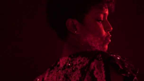 woman in sparkly dress in red light in nightclub - Filmati, video