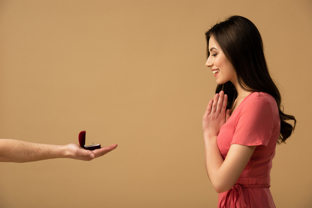 abgeschnittene Ansicht eines Mannes, der einem überraschten brünetten Mädchen einen Heiratsantrag macht  - Foto, Bild