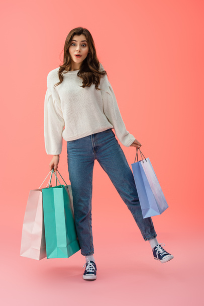 Vista completa de la mujer sorprendida y atractiva sosteniendo bolsas de compras sobre fondo rosa
  - Foto, Imagen