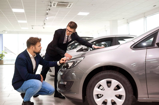  Customer and salesman choose a car in the showroom - Zdjęcie, obraz