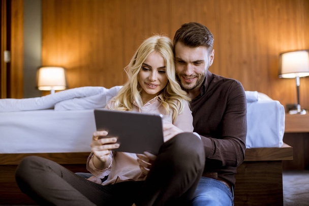 Romantico giovane coppia felice innamorata seduta sul pavimento a riposo e divertirsi navigando su internet
 - Foto, immagini