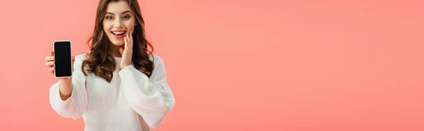 panoramic shot of smiling and beautiful woman in white sweater holding smartphone with copy space  isolated on pink - Foto, immagini