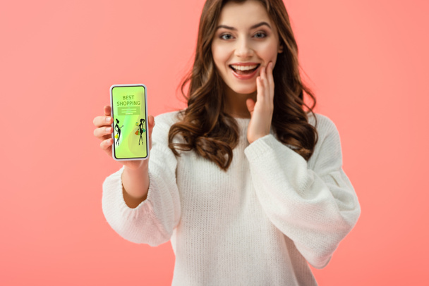 селективное внимание женщины в белом свитере, держащей смартфон с лучшим приложением для покупок на экране изолированы на розовый
  - Фото, изображение