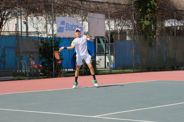 ISRAEL - Netanya, 27 de julho de 2018: um jovem de camisa esportiva e shorts esportivos está jogando na quadra de tênis no tênis
 - Foto, Imagem