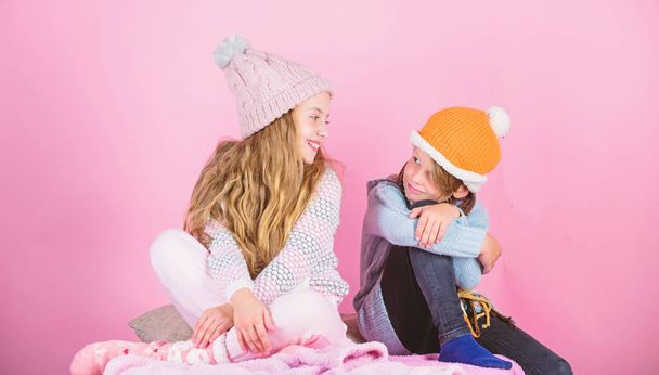 Warm up your winter wear with cute and cozy accessories. Siblings wear winter warm hats sit on pink background. Children boy and girl warm up with sweaters and hats. Stay warm and comfortable - Photo, Image