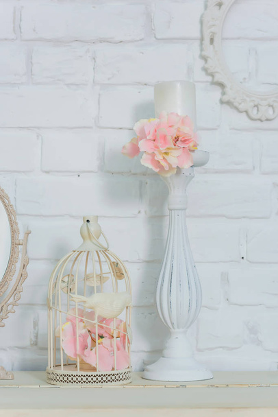 The interior of the room. Texture of white brick wall. Photo frames hanging on the wall. Wedding bouquet. White candlesticks. Oval mirror on stand. Decorative pink flowers. White piano. - Photo, Image