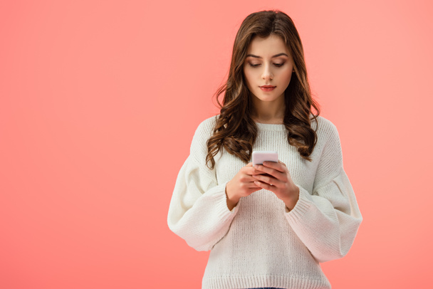 beautiful young woman in white sweater holding smartphone isolated on pink - Valokuva, kuva