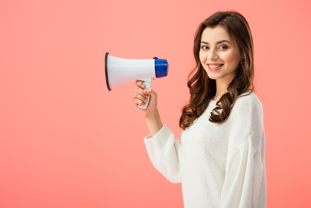 brunette woman in white sweater holding megaphone isolated on pink - Fotografie, Obrázek