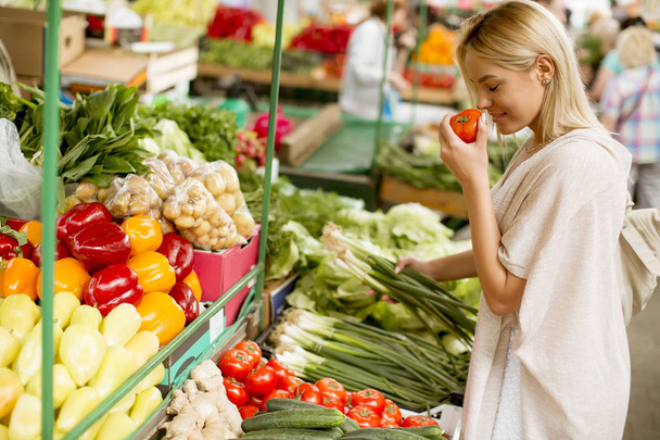 Ver en bastante joven mujer comprar verduras en el mercado
 - Foto, Imagen